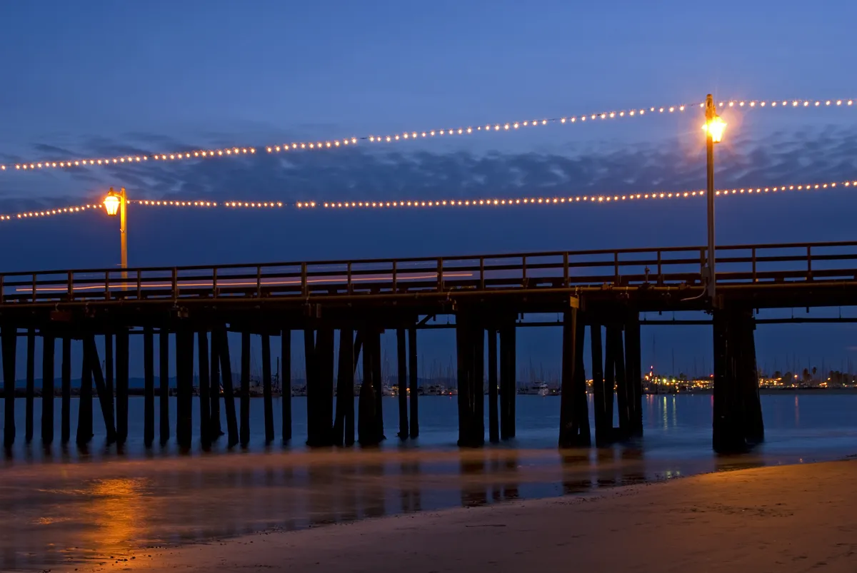 Strings of lights along Stearns Wharf glowing over the water at dusk in Santa Barbara