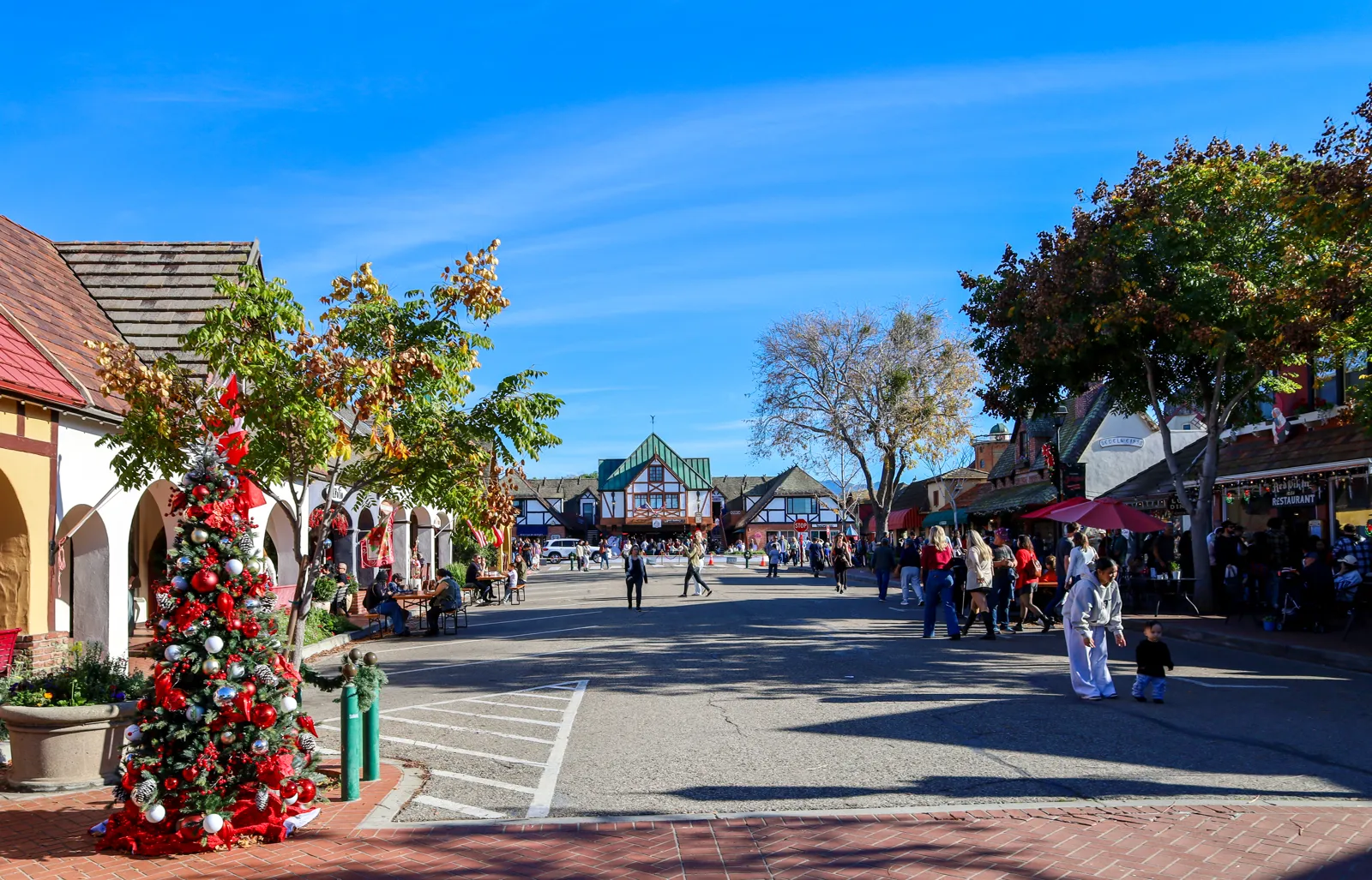 A Christmas tree and holiday decorations on a sunny street of Danish-style buildings in Solvang