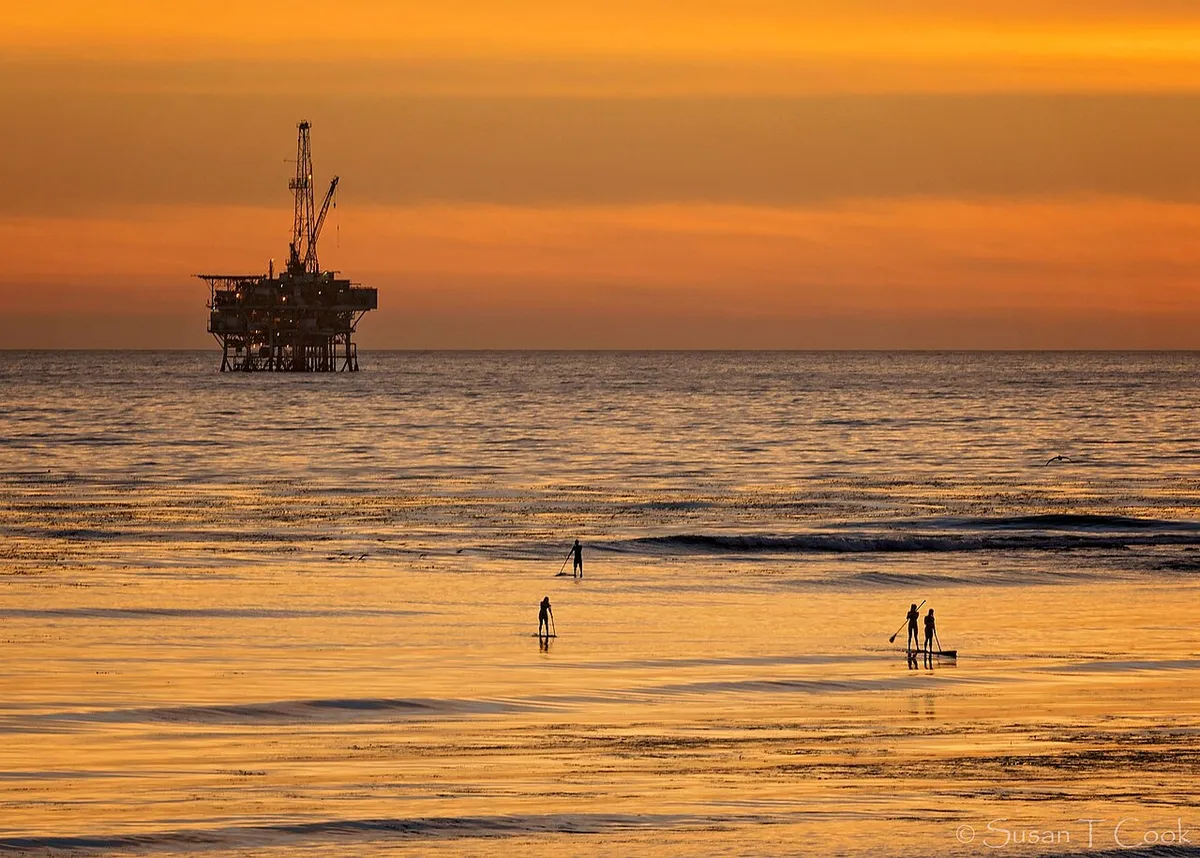 Paddleboarders silhouetted on calm water at sunset off the Santa Barbara coast